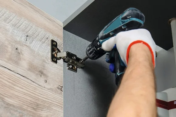 Person montiert Schranktür mit Akkuschreiber.